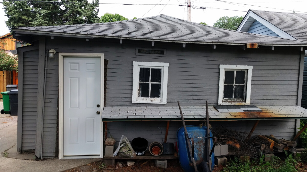 The new door installed in the garage, which is noticeably not aligned with the windows or roofline